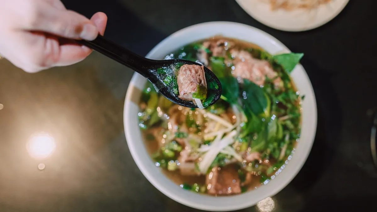 Bol de pho vietnamita con fideos de arroz, hierbas frescas y caldo